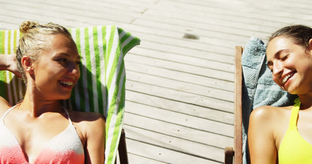 Young Women Relaxing on Loungers on Sunny Deck - Free Images, Stock Photos and Pictures on Pikwizard.com