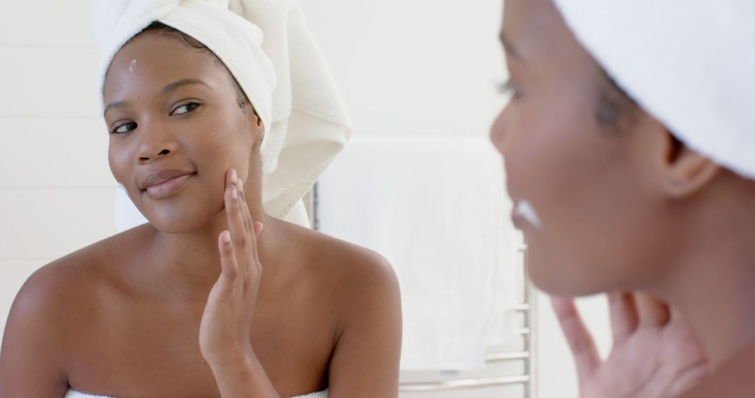 Woman Applying Skincare Cream in Bathroom, Wrapped in Towel - Free Images, Stock Photos and Pictures on Pikwizard.com