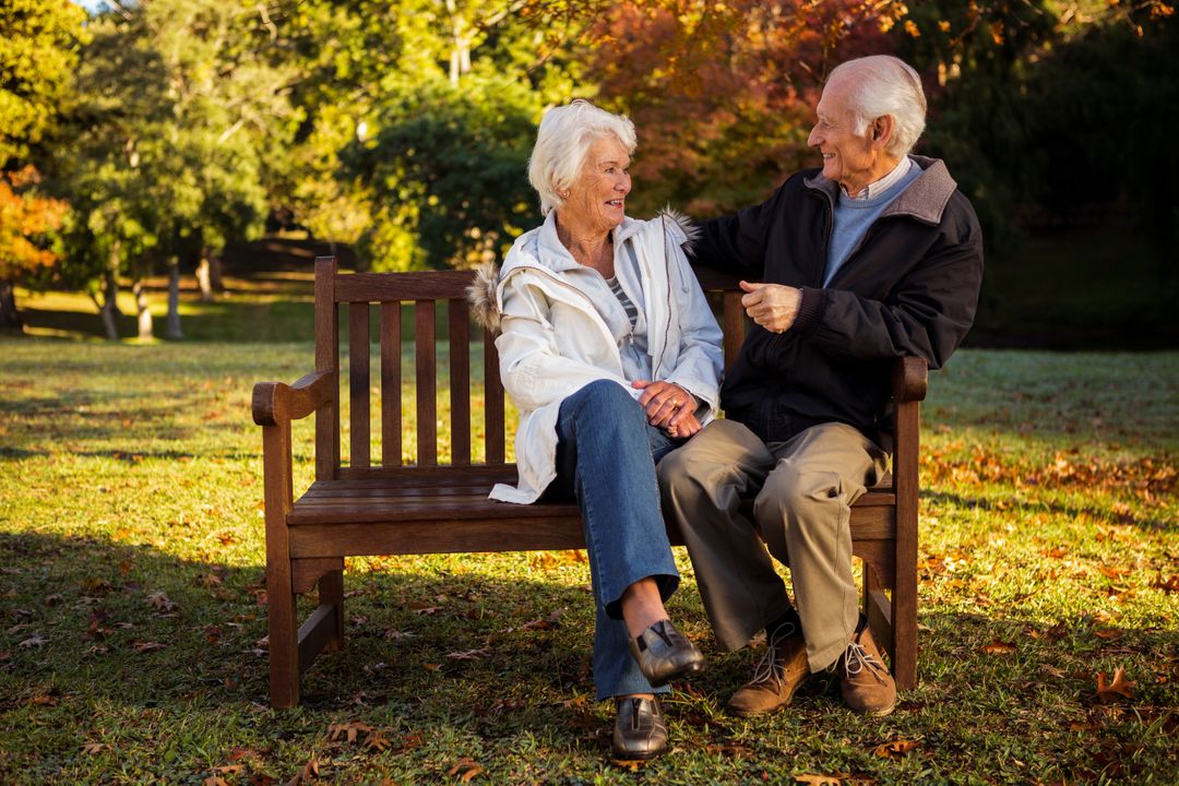 Elderly Couple Smiling on Park Bench in Autumn - Free Images, Stock Photos and Pictures on Pikwizard.com