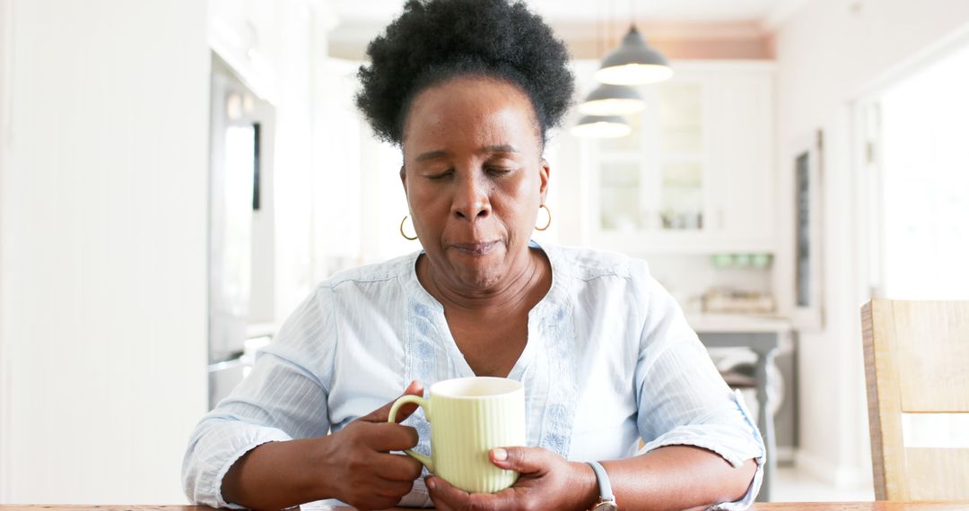 Senior Woman Relaxing with Hot Beverage in Kitchen - Free Images, Stock Photos and Pictures on Pikwizard.com