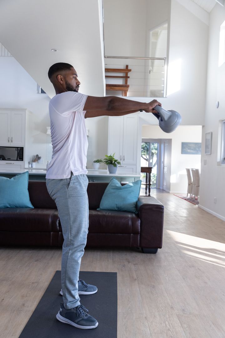 Athletic Man Executing Kettlebell Swing in Modern Living Space