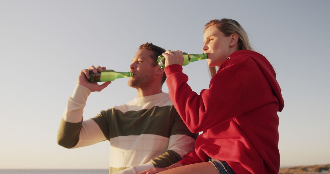 Young Couple Drinking Beers on Beach at Sunset - Free Images, Stock Photos and Pictures on Pikwizard.com