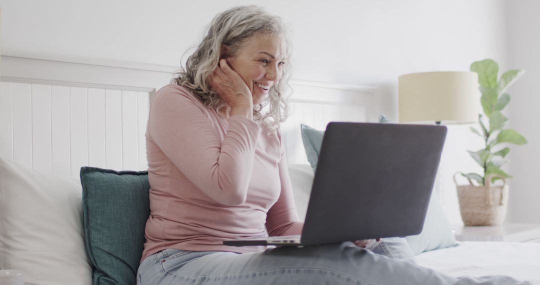 Cheerful Senior Woman Video Calling on Laptop from Cozy Bed - Free Images, Stock Photos and Pictures on Pikwizard.com