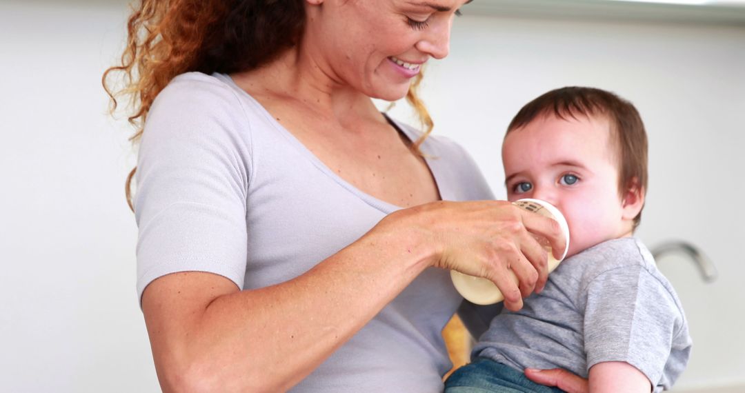 Smiling Mother Feeding Baby with Bottle in Home - Free Images, Stock Photos and Pictures on Pikwizard.com