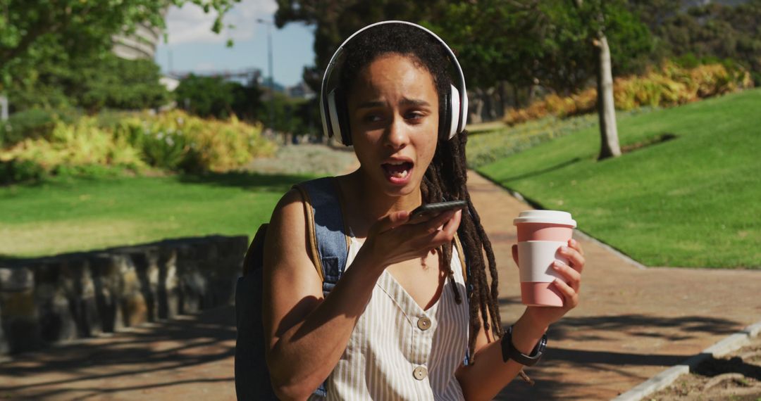 Excited Woman With Headphones Using Smartphone in Park - Free Images, Stock Photos and Pictures on Pikwizard.com