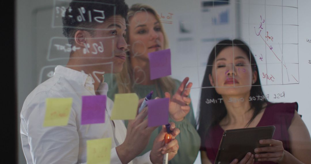 Creative Team Collaborative Brainstorming with Sticky Notes on Transparent Board