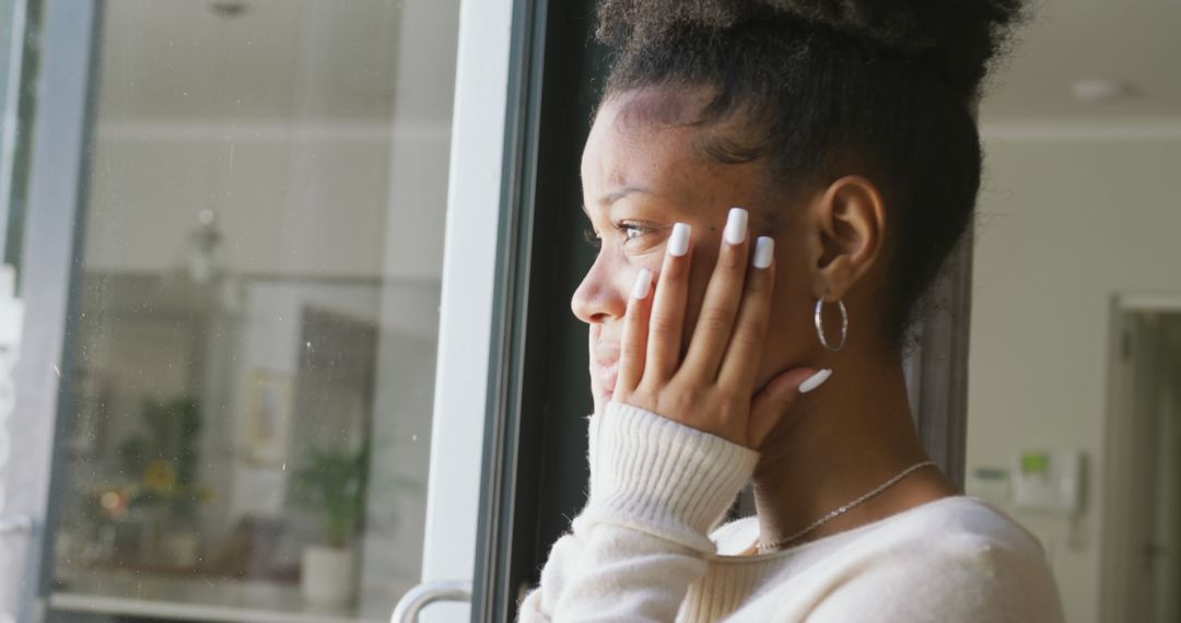 Image of crying african american woman looking outside window - Free Images, Stock Photos and Pictures on Pikwizard.com