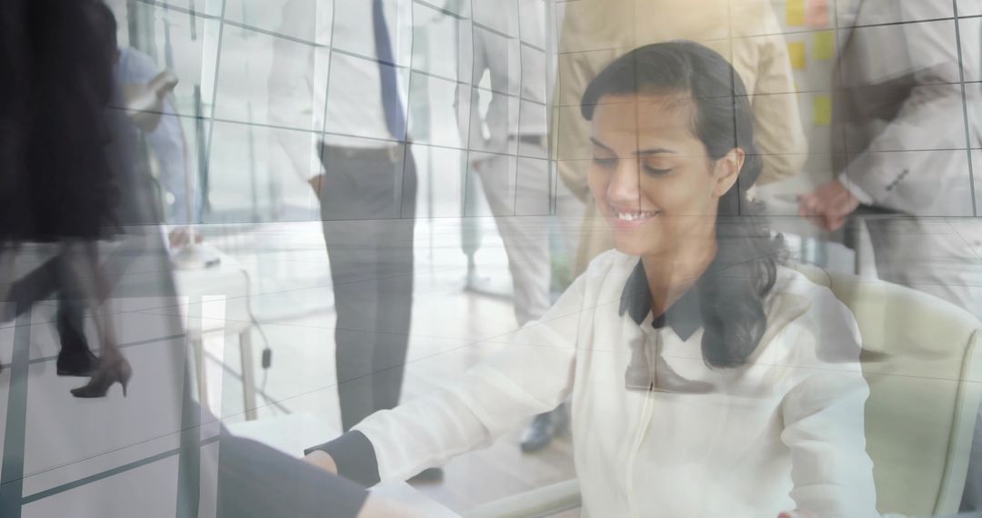 Smiling professional woman typing on laptop in modern glass office with reflections