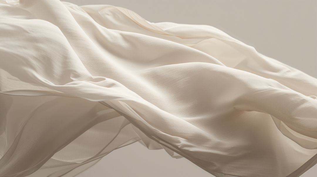 Cream silk chiffon fabric flowing and drifting in soft breeze with translucent texture