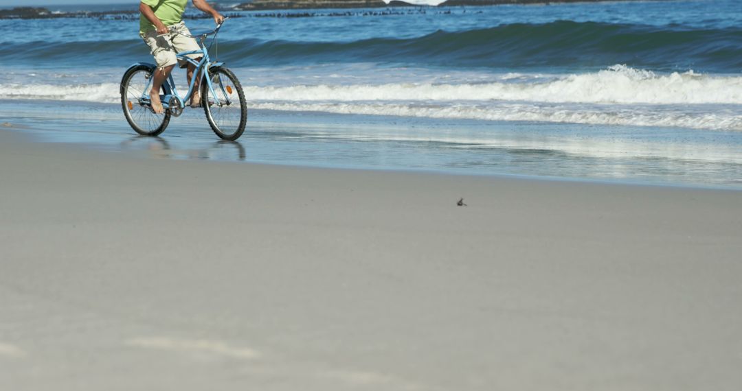 Man Riding Bike on Sandy Beach Near Ocean Waves on Sunny Day - Free Images, Stock Photos and Pictures on Pikwizard.com