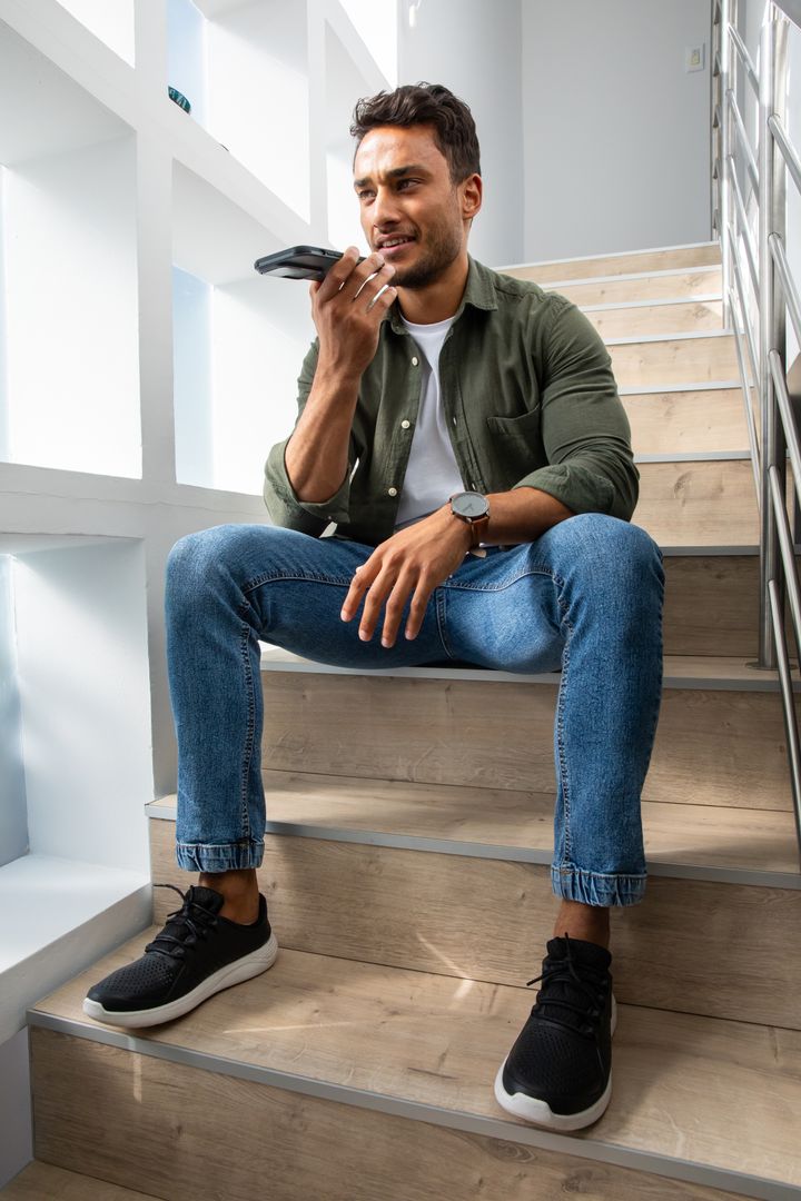 Casually Dressed Man Sitting in Stairwell Using Smartphone Voice Commands