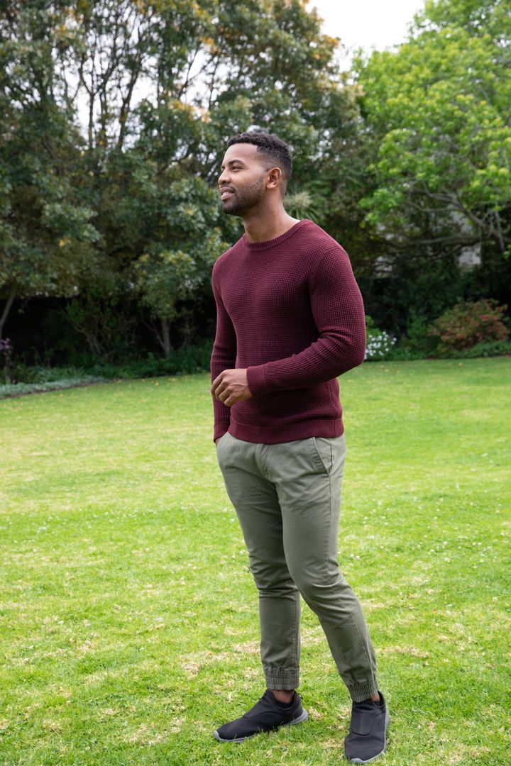 Man in Maroon Sweater Relaxing in Green Backyard