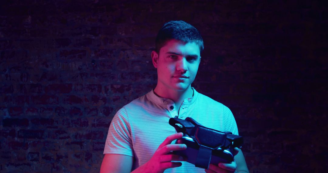 Young Man Holding Virtual Reality Headset in Neon Light - Free Images, Stock Photos and Pictures on Pikwizard.com