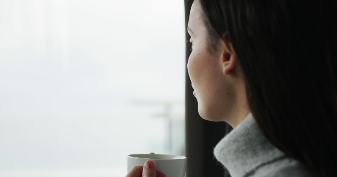 Woman Relaxing by Large Window with Cup of Coffee - Free Images, Stock Photos and Pictures on Pikwizard.com