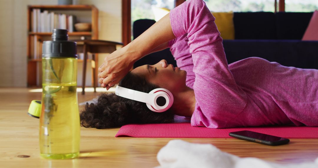 Woman Lying on Exercise Mat with Headphones and Water Bottle - Free Images, Stock Photos and Pictures on Pikwizard.com