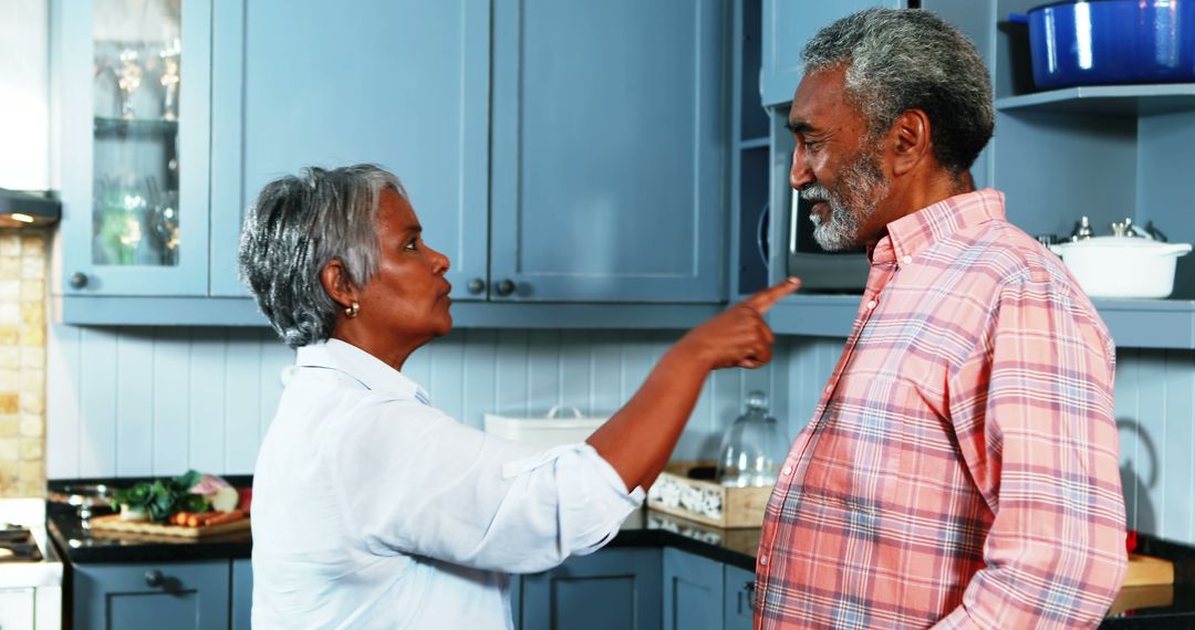 Elderly couple arguing in kitchen with serious expressions - Free Images, Stock Photos and Pictures on Pikwizard.com