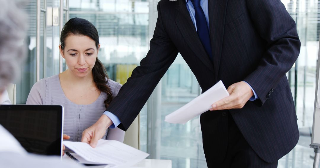 Businessman Handing Documents to Colleague In Modern Office - Free Images, Stock Photos and Pictures on Pikwizard.com