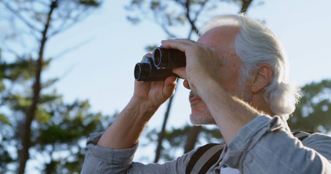 Senior Man Using Binoculars in Forest Observing Nature - Free Images, Stock Photos and Pictures on Pikwizard.com