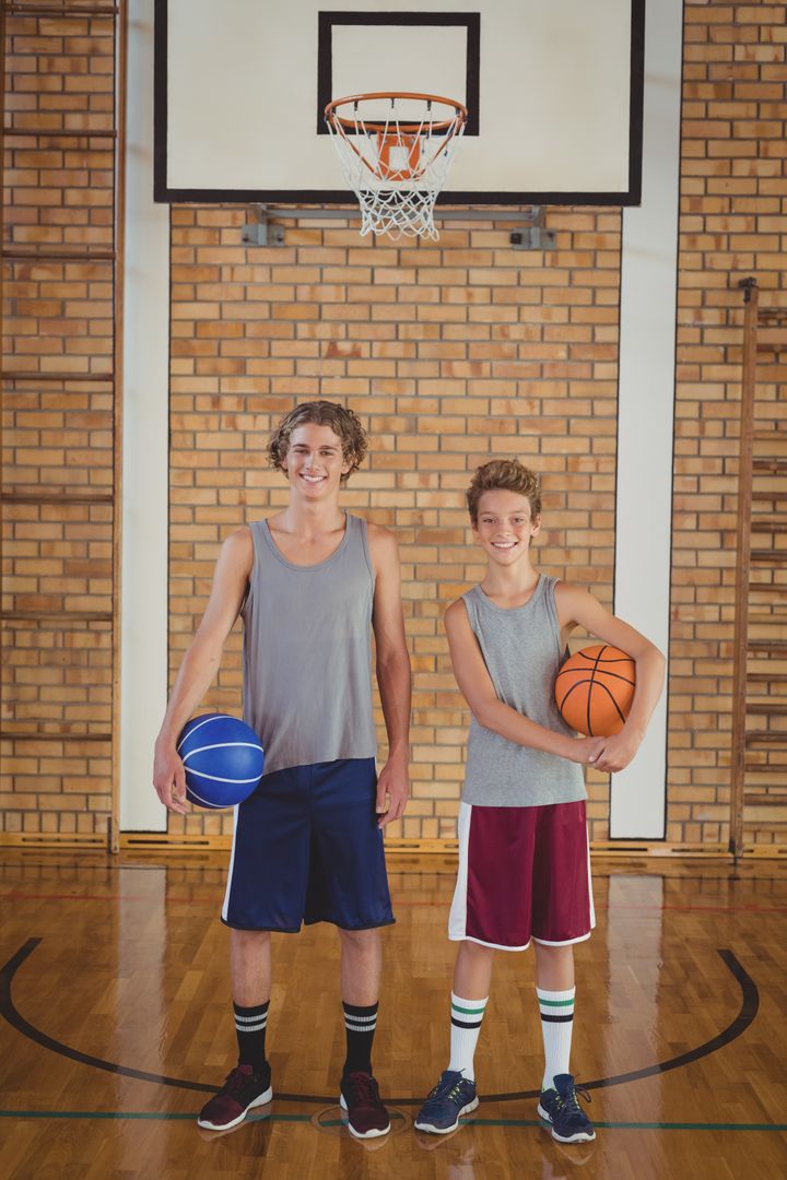 Smiling school boys holding basketball in the court - Free Images, Stock Photos and Pictures on Pikwizard.com