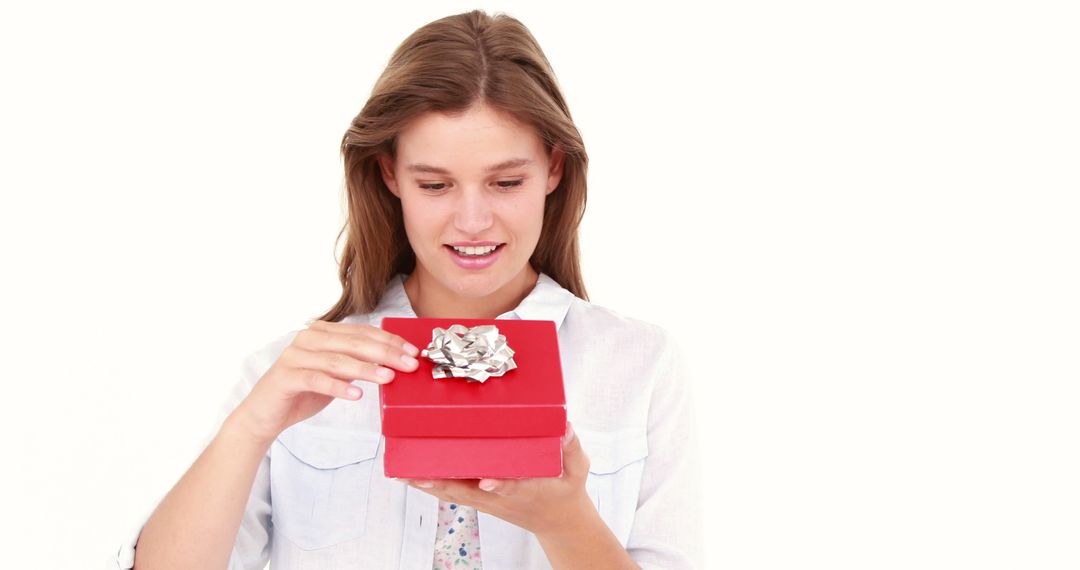 Happy Young Woman Opening Red Gift Box with Silver Bow - Free Images, Stock Photos and Pictures on Pikwizard.com