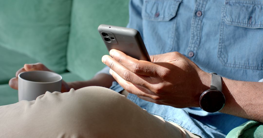 Man Relaxing at Home with Smartphone and Coffee Mug