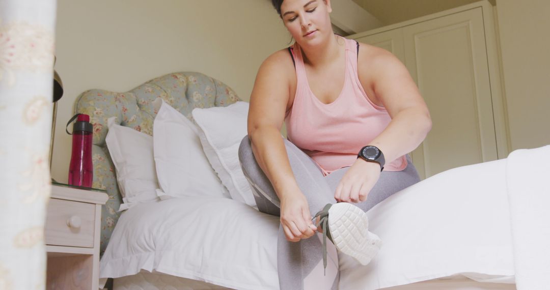 Woman Tying Shoes on Bed in Bedroom Preparing for Workout - Free Images, Stock Photos and Pictures on Pikwizard.com