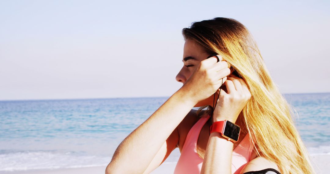 Woman Preparing for Workout Using Earbuds at Beach - Free Images, Stock Photos and Pictures on Pikwizard.com