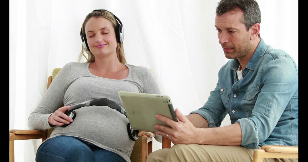 Pregnant Couple Enjoying Music with Tablet and Headphones - Free Images, Stock Photos and Pictures on Pikwizard.com