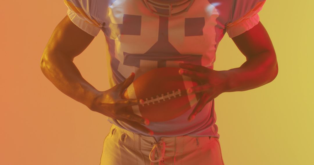 American football player holding football in colorful lighting - Free Images, Stock Photos and Pictures on Pikwizard.com