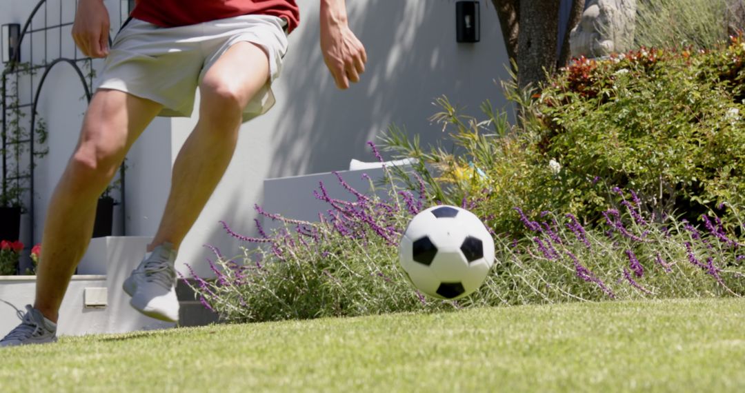 Active Man Practicing Football Skills Outdoors in a Sunny Garden