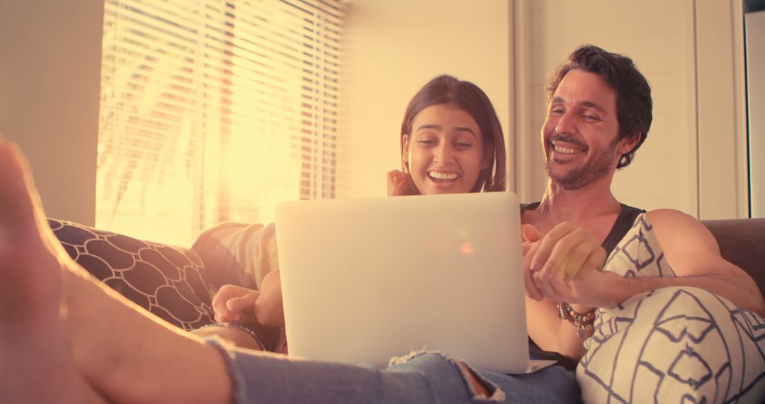 Couple Relaxing and Laughing with Laptop on Sofa