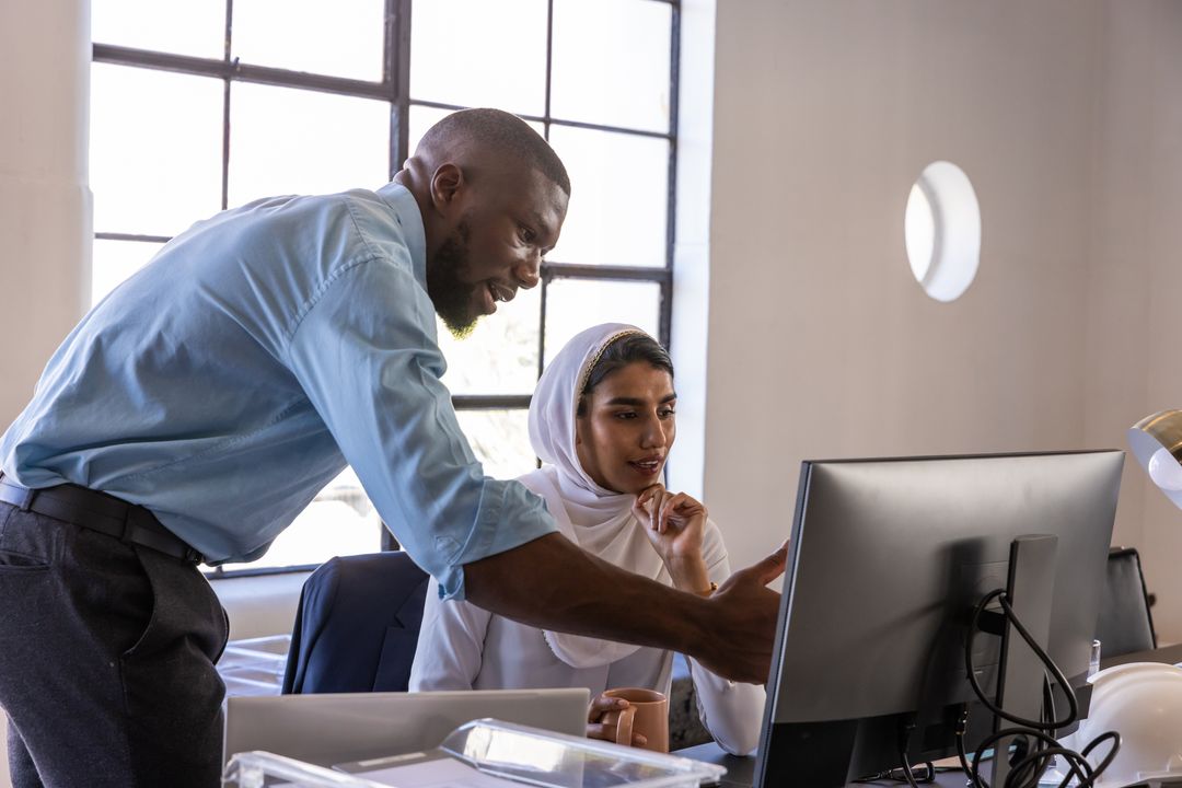 Diverse Professionals Collaborating Over Computer in Modern Office