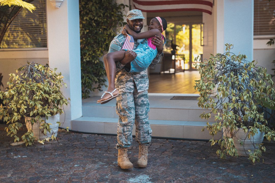 Happy african american soldier father holding daughter outside their house - Free Images, Stock Photos and Pictures on Pikwizard.com