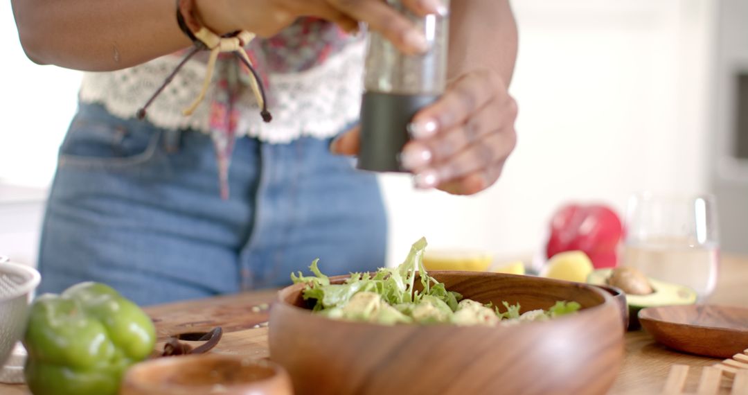 Woman Seasoning Fresh Salad in Modern Kitchen Setting
