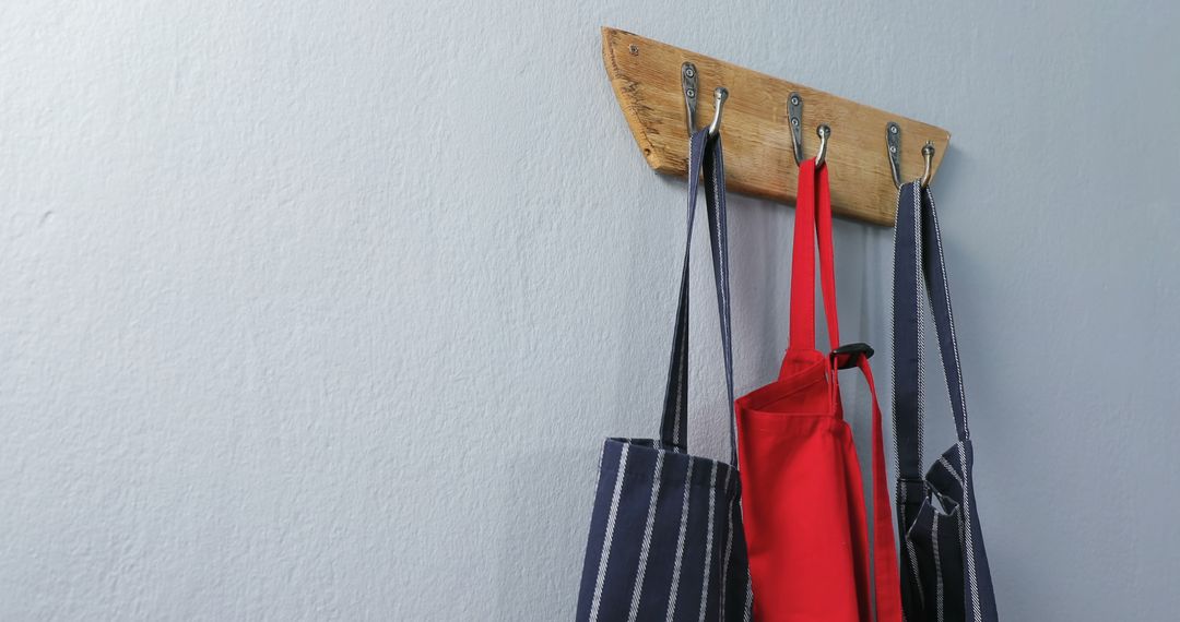 Aprons hanging on hook rack against light blue wall - Free Images, Stock Photos and Pictures on Pikwizard.com