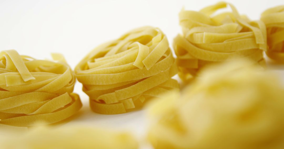 Close-Up View of Fettuccine Pasta Nests on White Background - Free Images, Stock Photos and Pictures on Pikwizard.com