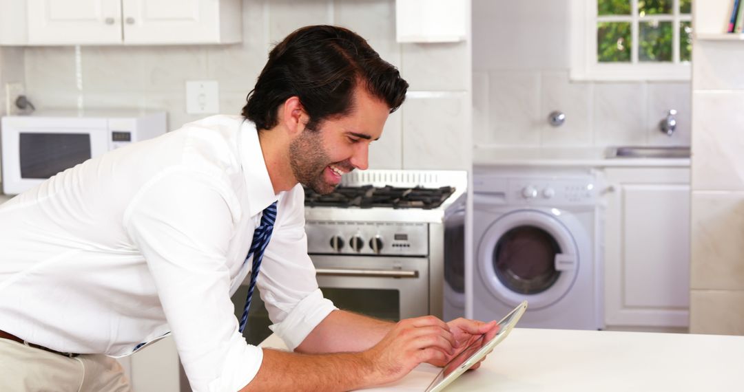 Man Using Tablet in Modern Kitchen for Work - Free Images, Stock Photos and Pictures on Pikwizard.com