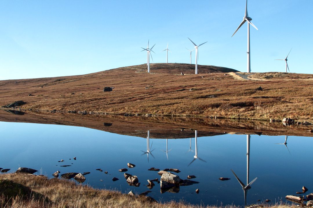 Wind Turbines on Hill Reflecting in Calm Lake - Free Images, Stock Photos and Pictures on Pikwizard.com