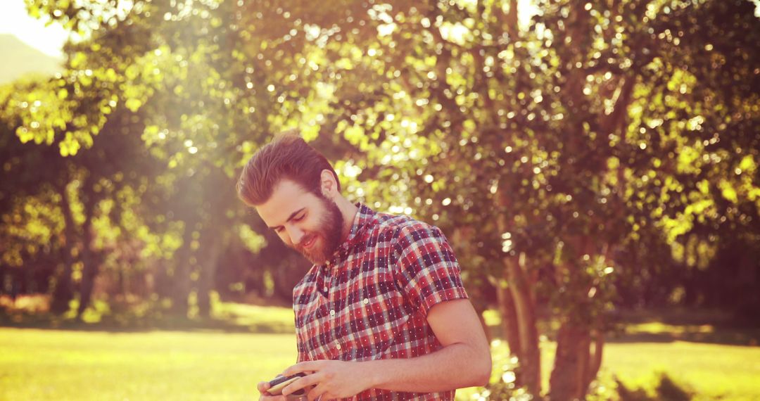 Bearded Man Using Smartphone in Sunlit Park - Free Images, Stock Photos and Pictures on Pikwizard.com