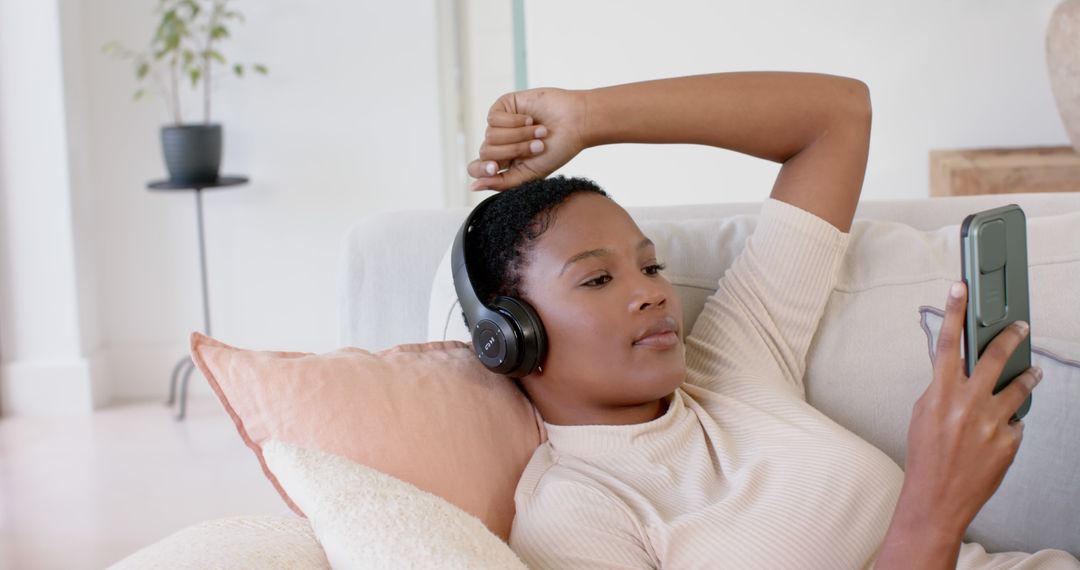 Relaxed Young Woman with Headphones Using Smartphone on Couch - Free Images, Stock Photos and Pictures on Pikwizard.com