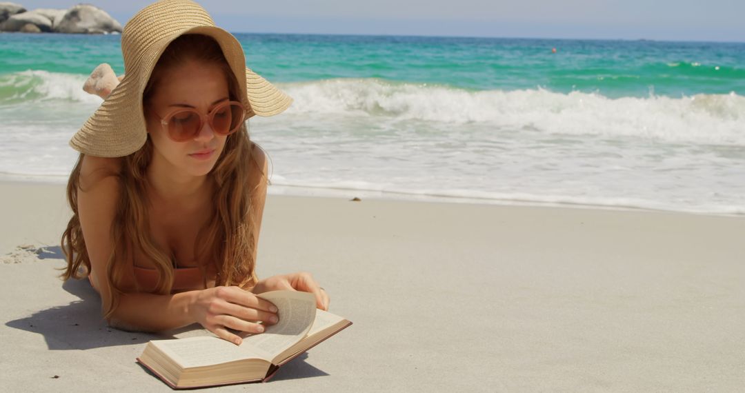 Woman Relaxing on Beach Reading Book in Sun Hat