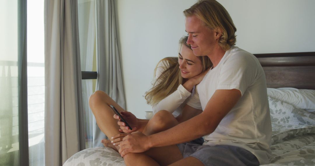 Young Couple Relaxing on Bed Using Smartphone - Free Images, Stock Photos and Pictures on Pikwizard.com