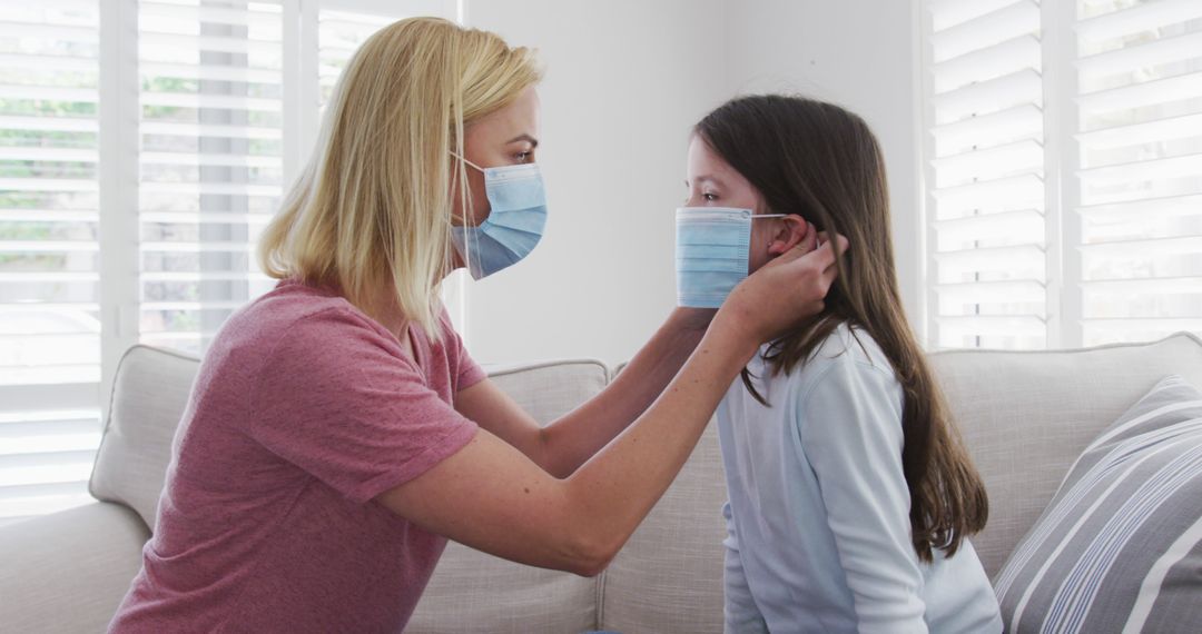 Mother Adjusting Face Mask on Young Daughter at Home - Free Images, Stock Photos and Pictures on Pikwizard.com