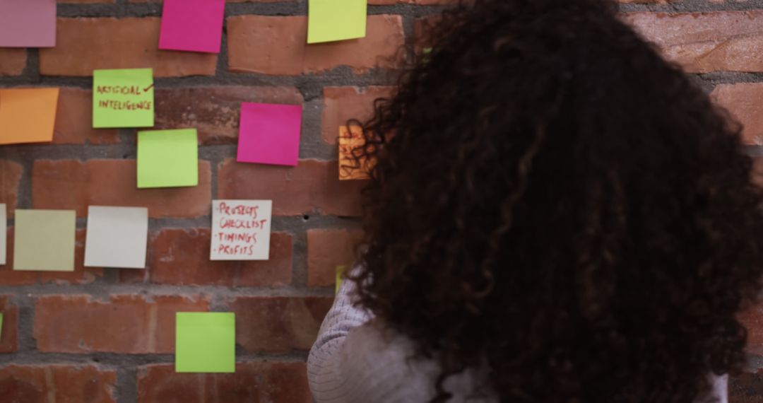 Person brainstorming with colorful sticky notes on brick wall - Free Images, Stock Photos and Pictures on Pikwizard.com