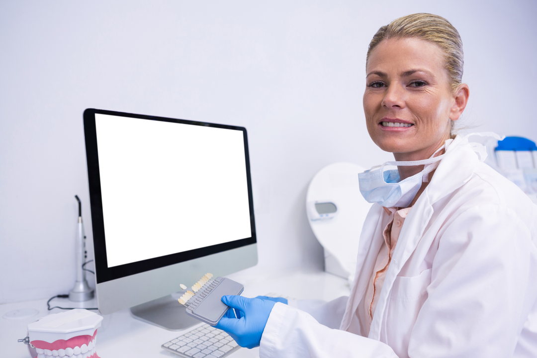 Dentist in Clinic Sitting by Computer Displaying Dental Caps - Download Free Stock Images Pikwizard.com