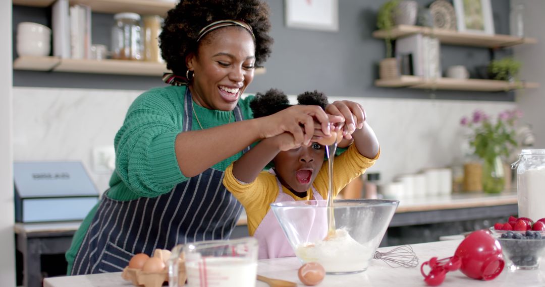 Smiling African American Mother Cooking with Child in Modern Kitchen - Free Images, Stock Photos and Pictures on Pikwizard.com