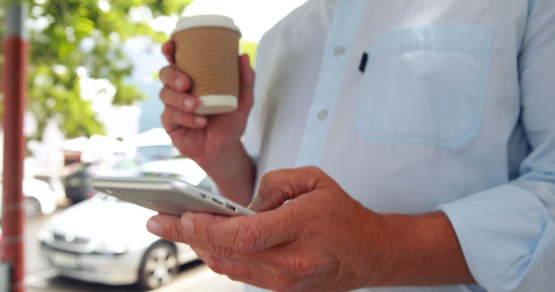 Man Holding Coffee Cup while Using Smartphone in Urban Setting - Free Images, Stock Photos and Pictures on Pikwizard.com