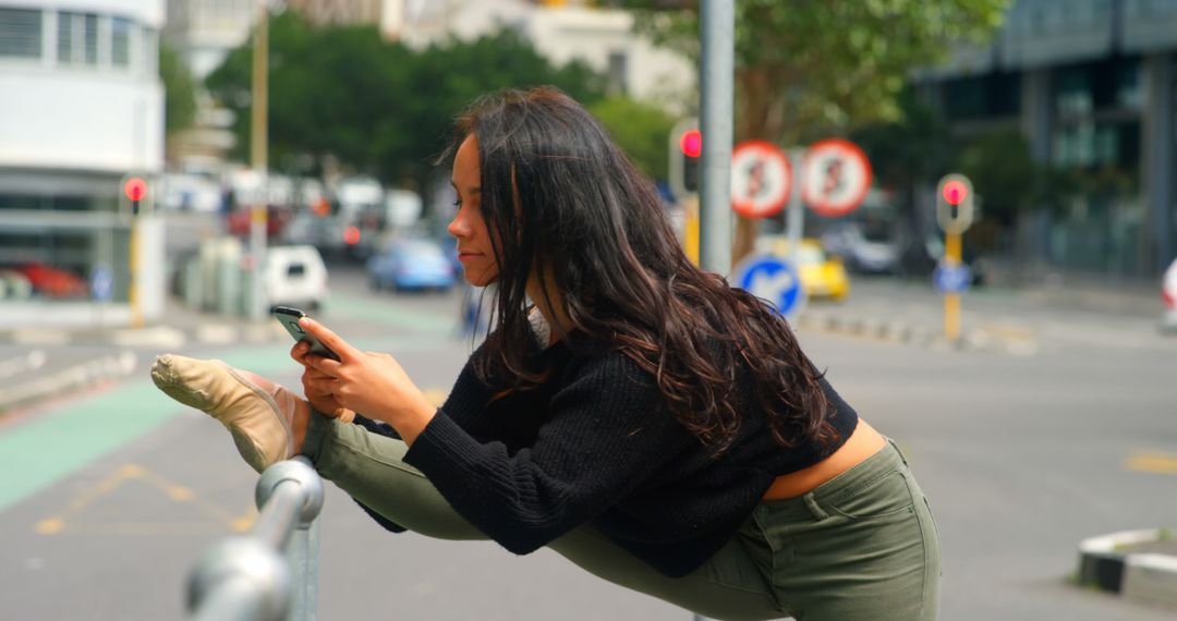 Beautiful woman using mobile phone while leg stretched on a railings in the city - Free Images, Stock Photos and Pictures on Pikwizard.com