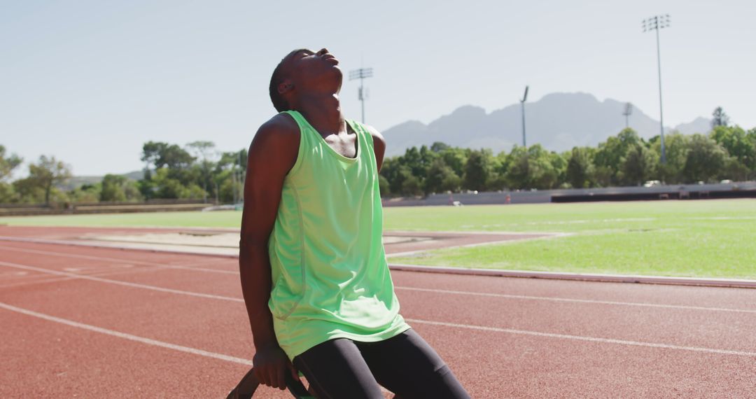 Athlete with Prosthetic Legs Resting at Track Field After Training
