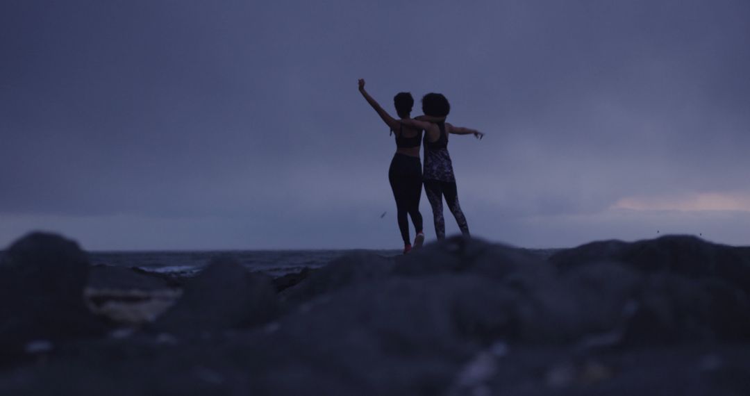 Two Friends Embracing on Rocky Beach at Dusk - Free Images, Stock Photos and Pictures on Pikwizard.com